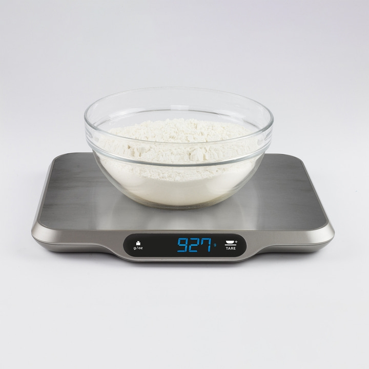 Scale with bowl and flour, showing 927 g, isolated on white background