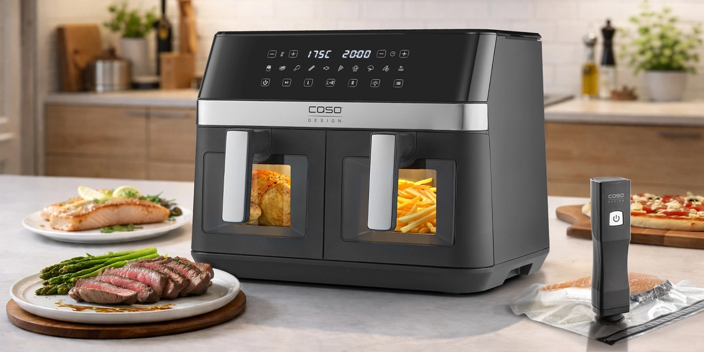A silver and black dual-basket air fryer cooker with one basket containing a chicken and the other fries.