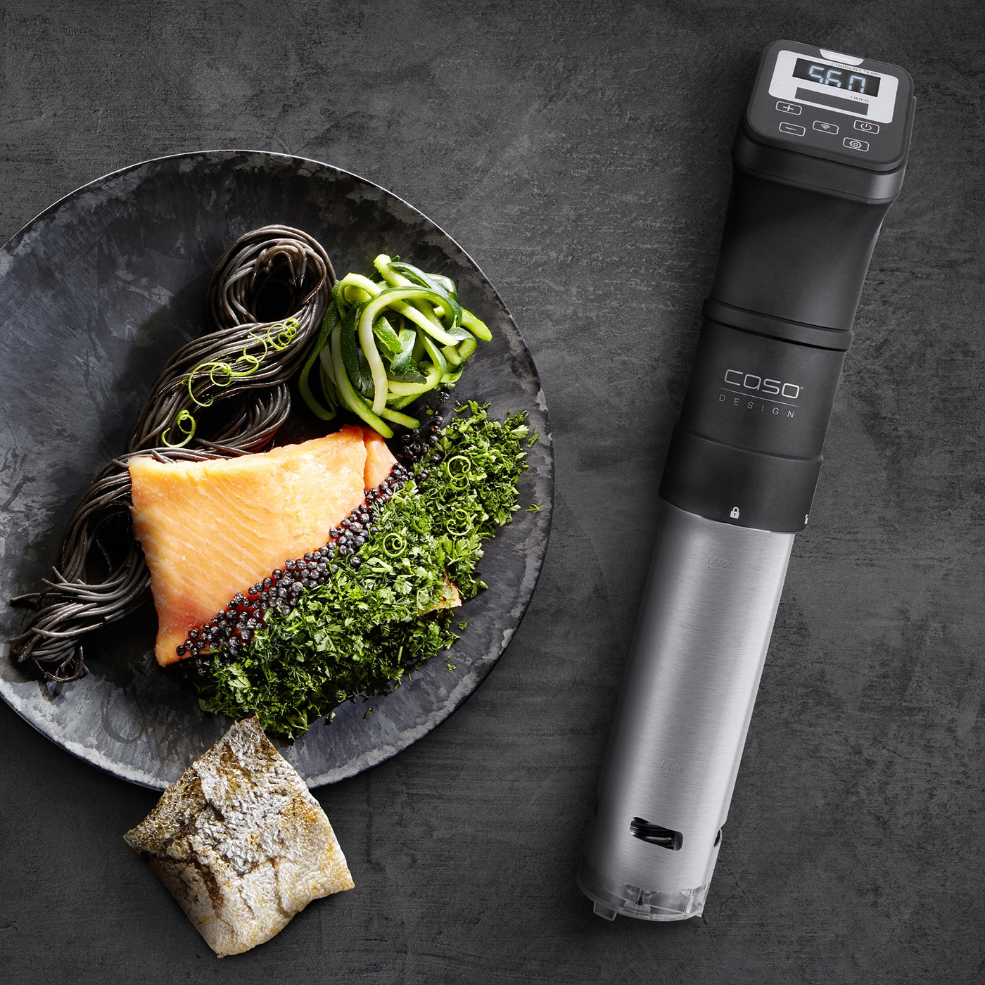 Lachsgericht mit Nudeln, Gemüse und Sous-Vide-Garer auf dunklem Hintergrund