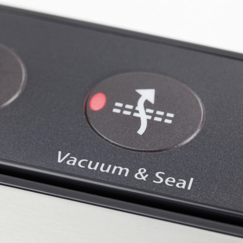 Close-up of vacuum and seal button with symbol and text on a device.