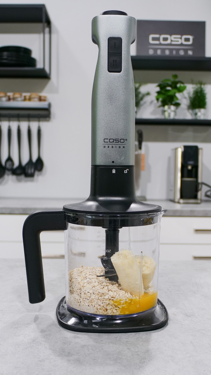 Blender with ingredients: oats, banana, and liquid in a container.