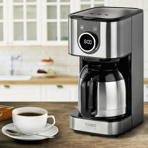 Coffee machine with a cup of coffee on a wooden table in the kitchen.
