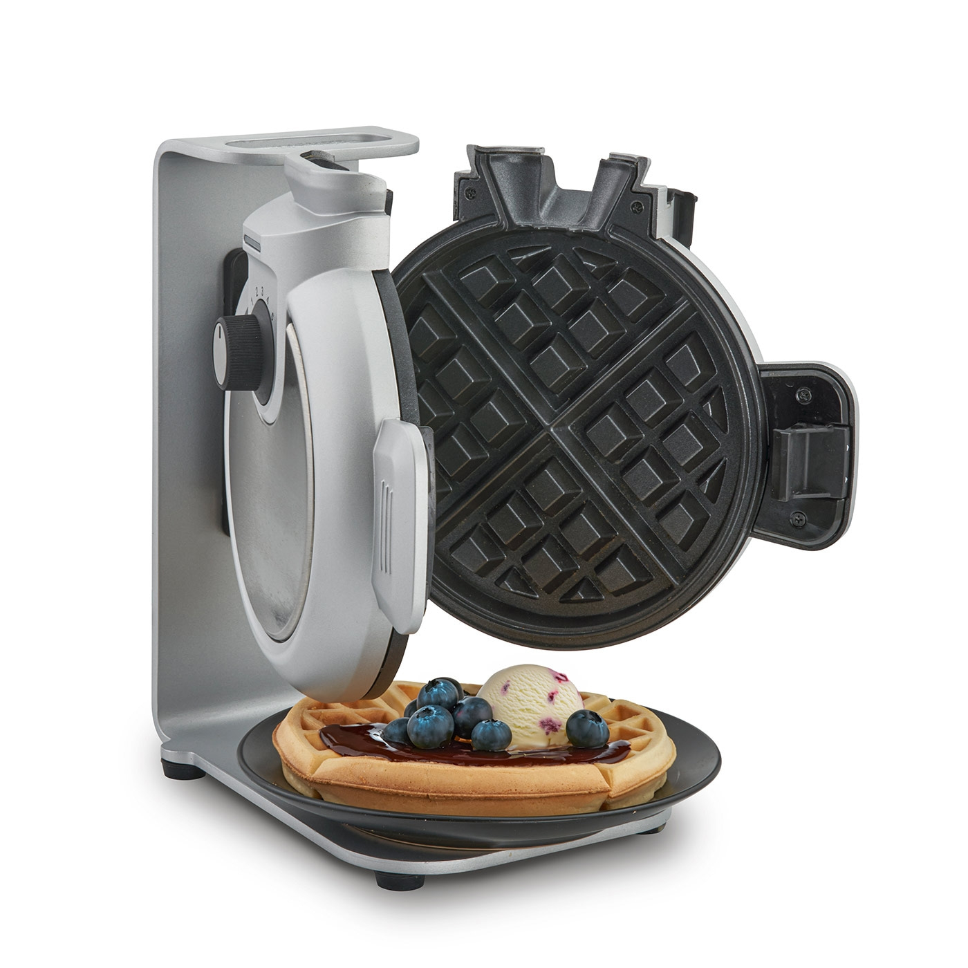 Waffle iron with waffle, ice cream, and blueberries on a plate. Delicious!