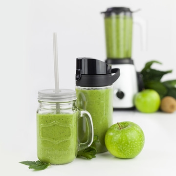 Grüner Smoothie mit Apfel, Kiwi und Mixer auf weißem Hintergrund