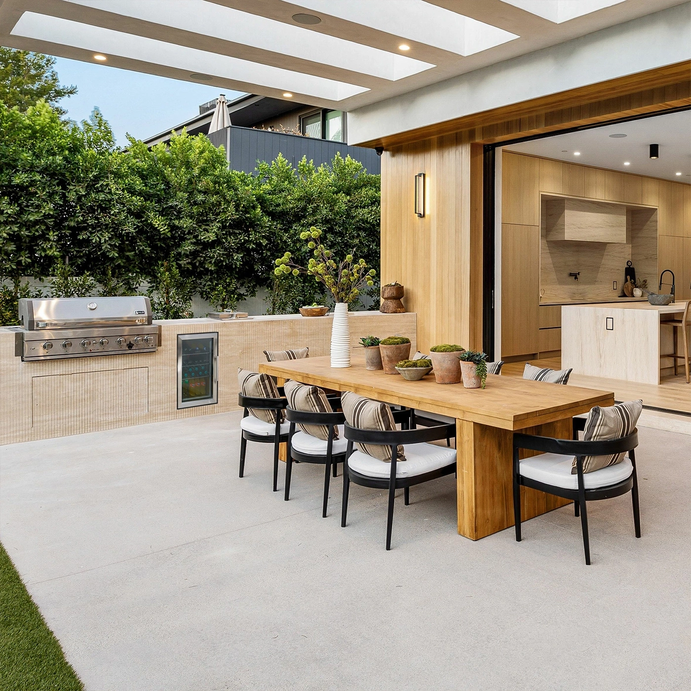 Moderne Terrasse mit Grill, Esstisch und Blick auf die Küche.