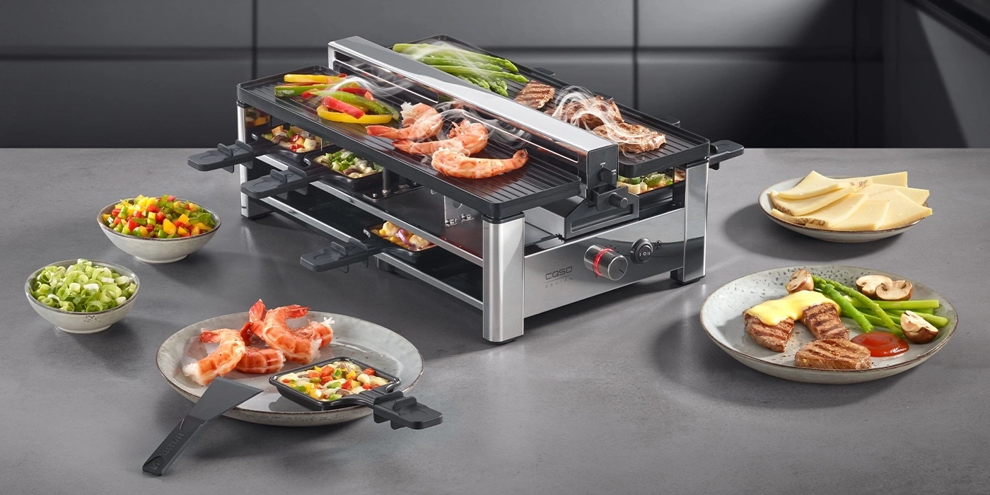 Ein Raclette-Grill mit Fleisch, Garnelen, Gemüse und Käse.