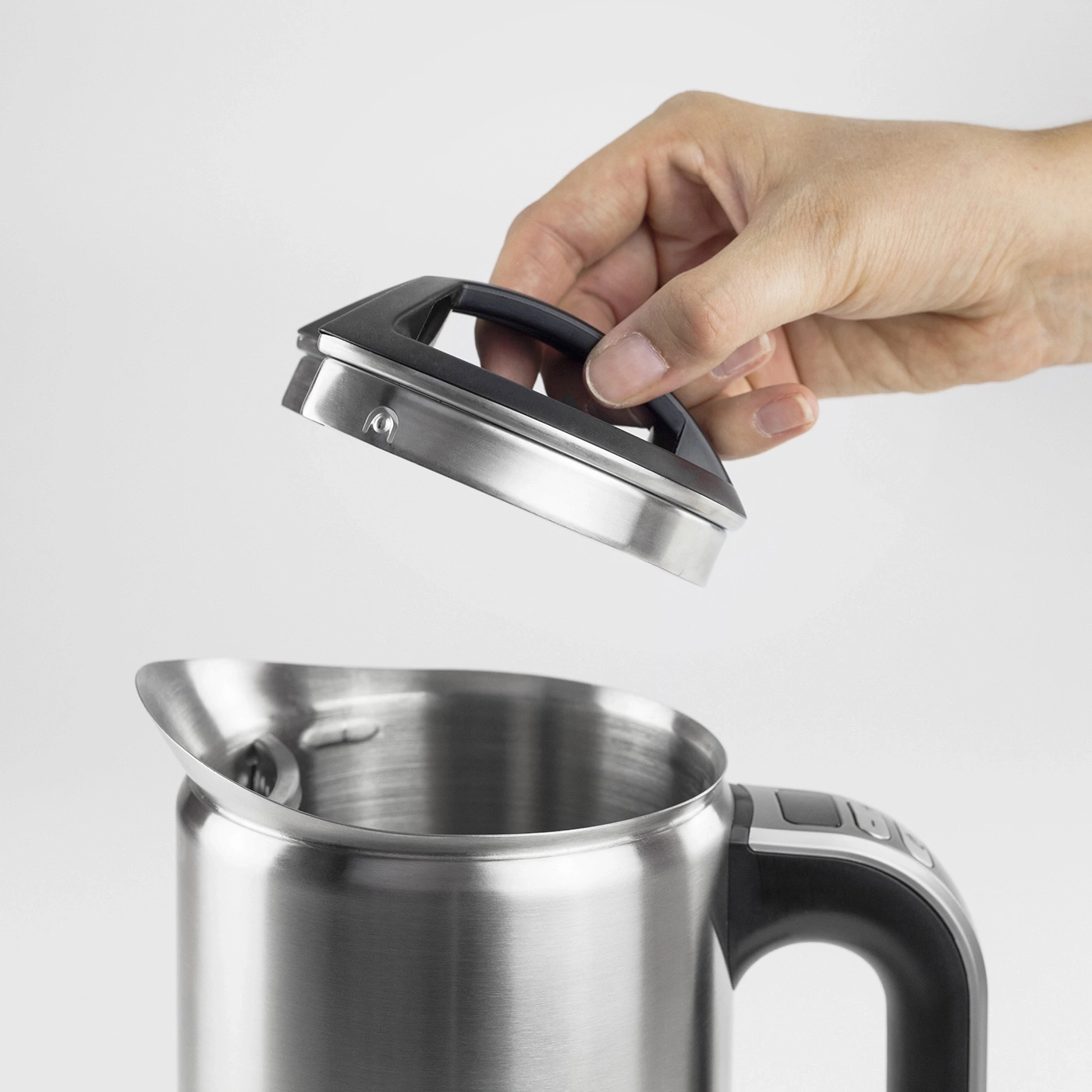 Hand lifting the lid of a stainless steel kettle, close-up, isolated