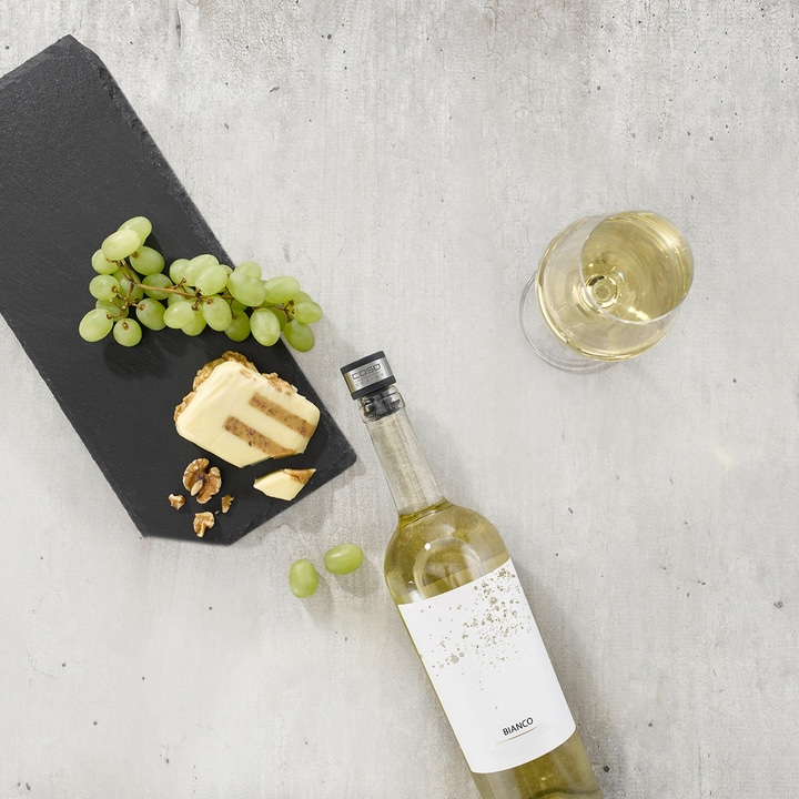White wine, grapes, cheese, and nuts on a gray background