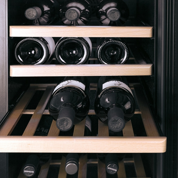 Wine cooler with multiple bottles stored on wooden shelves, close-up shot.