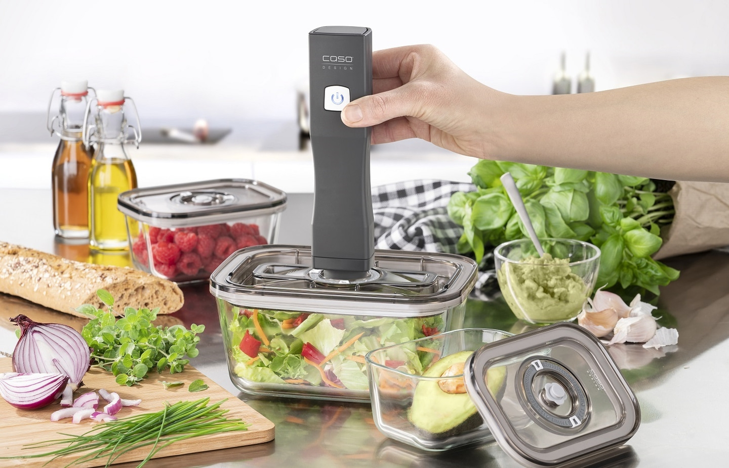 Fresh food in glass containers with vacuum sealer and accessories on a table.