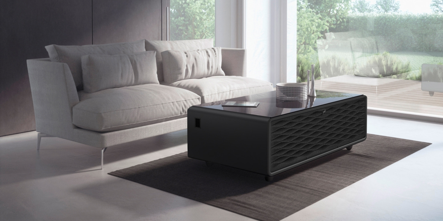Black table with wave pattern in front of a sofa and a window