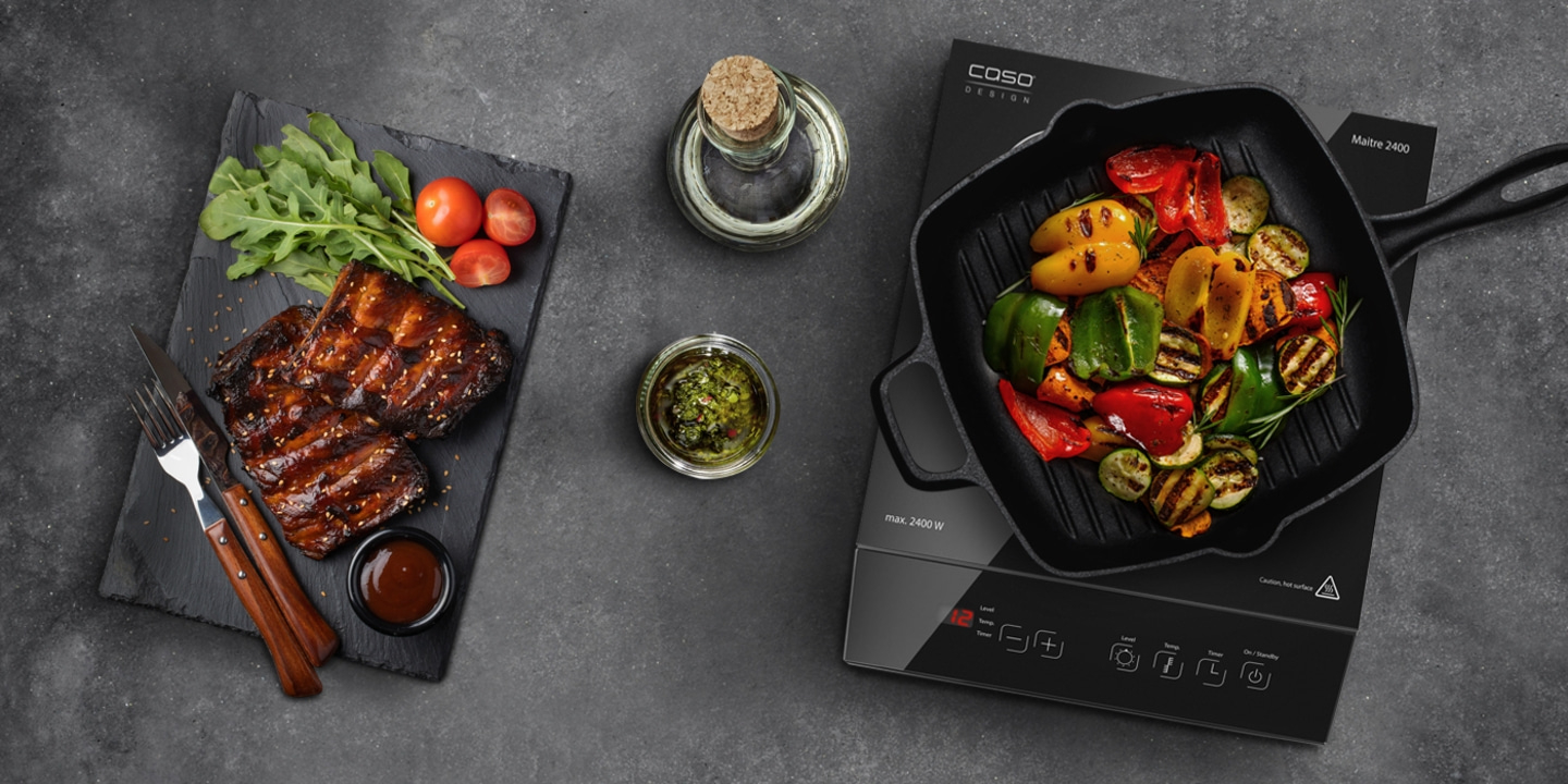 Gegrilltes Gemüse und Rippchen auf einem Tisch mit Soßen und Öl.