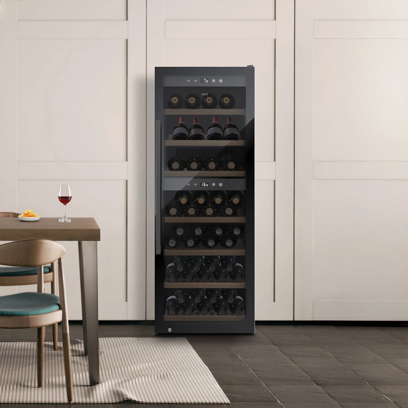 Ein Weinkühlschrank mit Flaschen und einem Glas Wein auf einem Tisch.