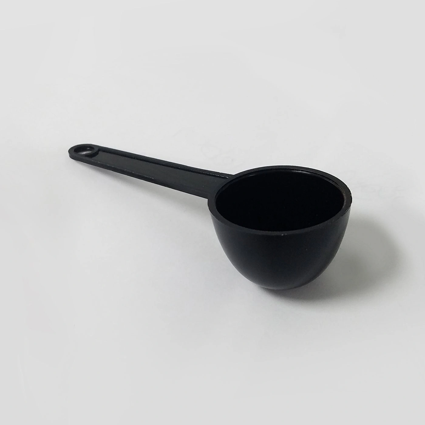 Black measuring spoon on white background, close-up, isolated