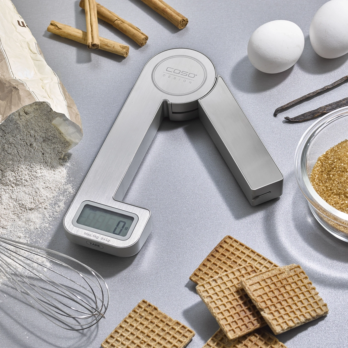 Küchenwaage mit Zutaten wie Eiern, Zimtstangen und Zucker für Backen.