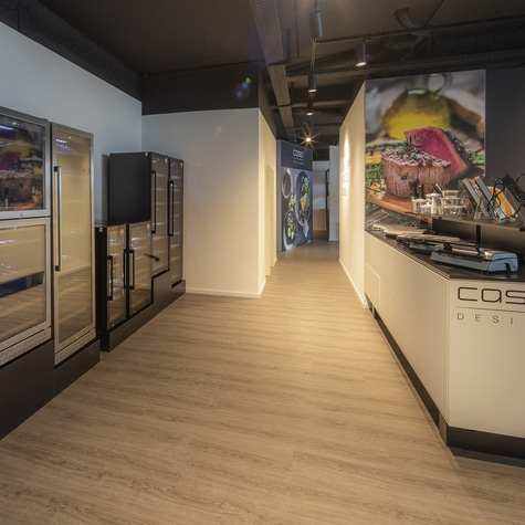 Interior with refrigerators, kitchen, and advertising boards. Wooden floor and lighting.