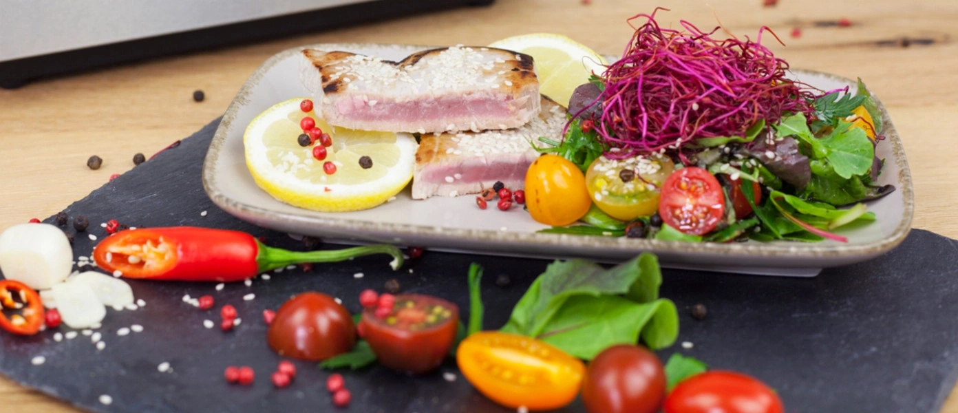 Gebratenes Thunfischsteak mit Salat und Tomaten auf einem Teller