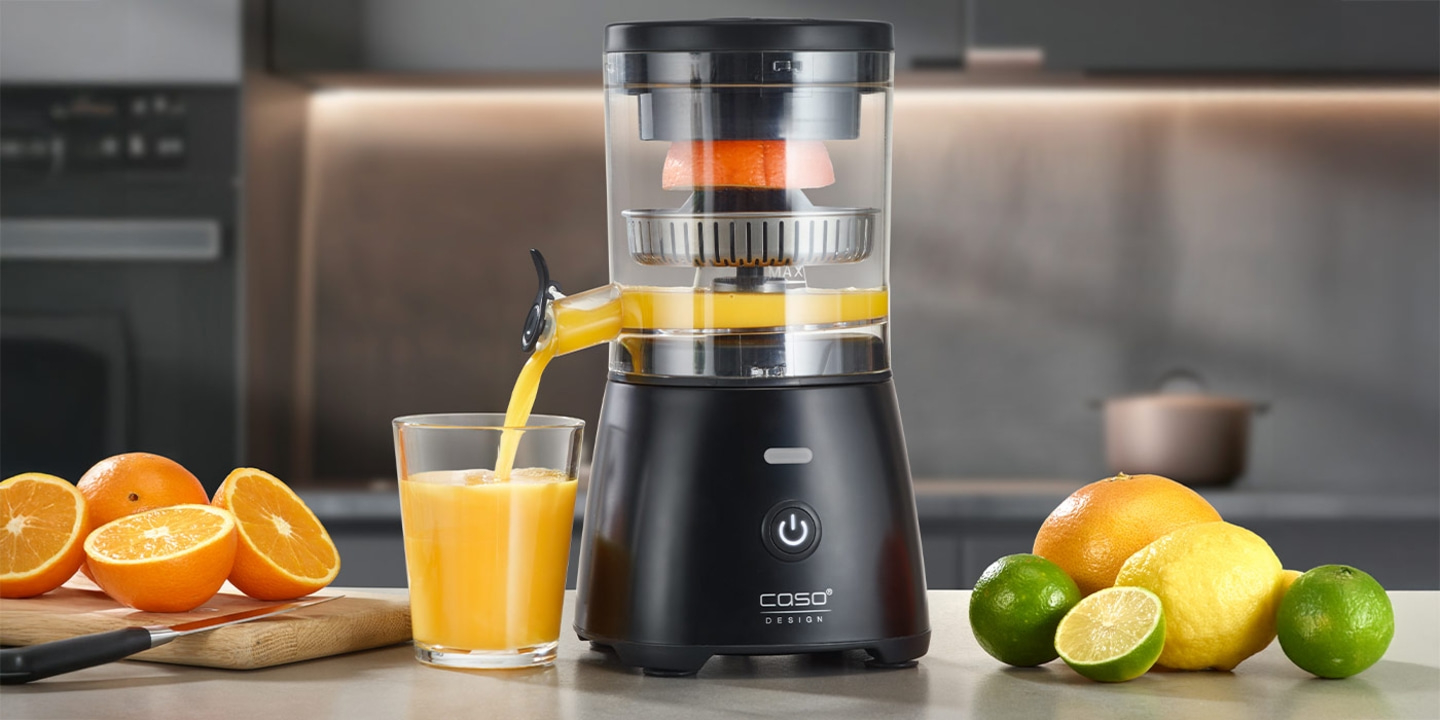 Juicer with oranges and citrus fruits, squeezing juice into a glass.