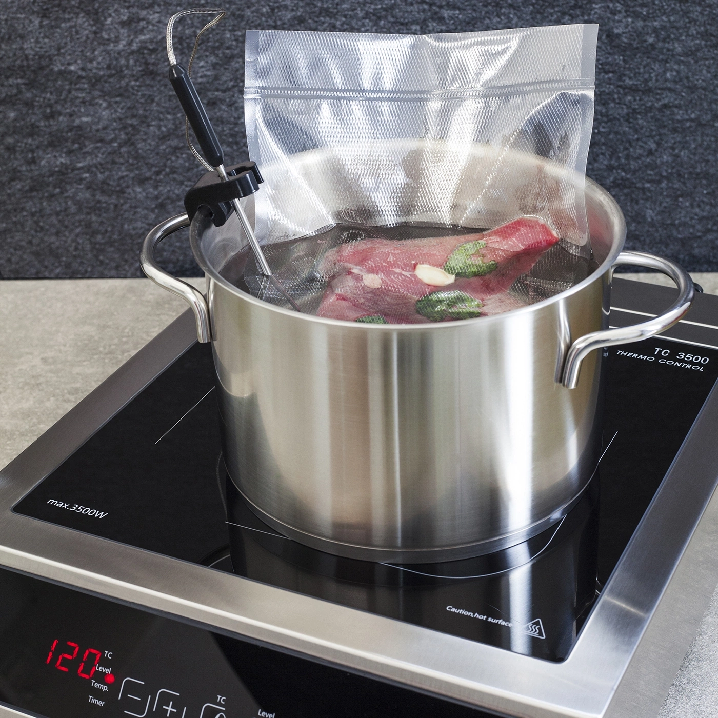 Topf mit Fleisch im Wasserbad auf Induktionskochfeld mit Temperaturanzeige