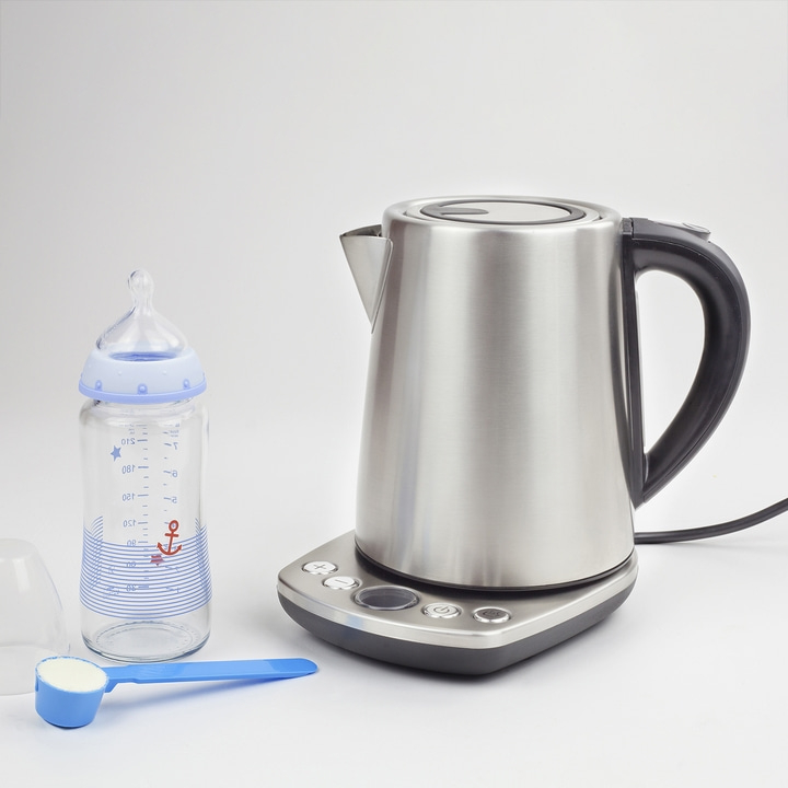 Babyflasche, Wasserkocher, Messlöffel mit Milchpulver auf weißem Hintergrund