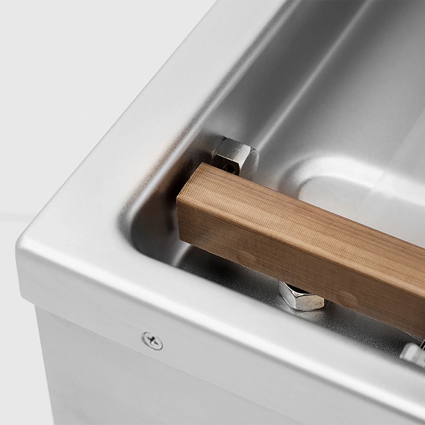 Nahaufnahme einer Edelstahlwanne mit Holz und Schraubenmuttern
