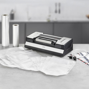 Vacuum sealer with accessories and bags on a gray surface.