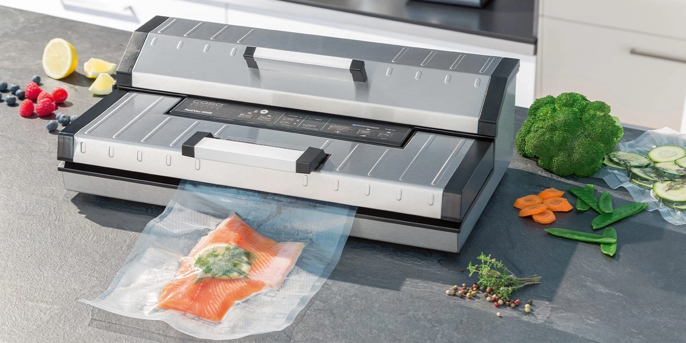 Vakuumiergerät mit Gemüse und Fisch auf einer Arbeitsplatte