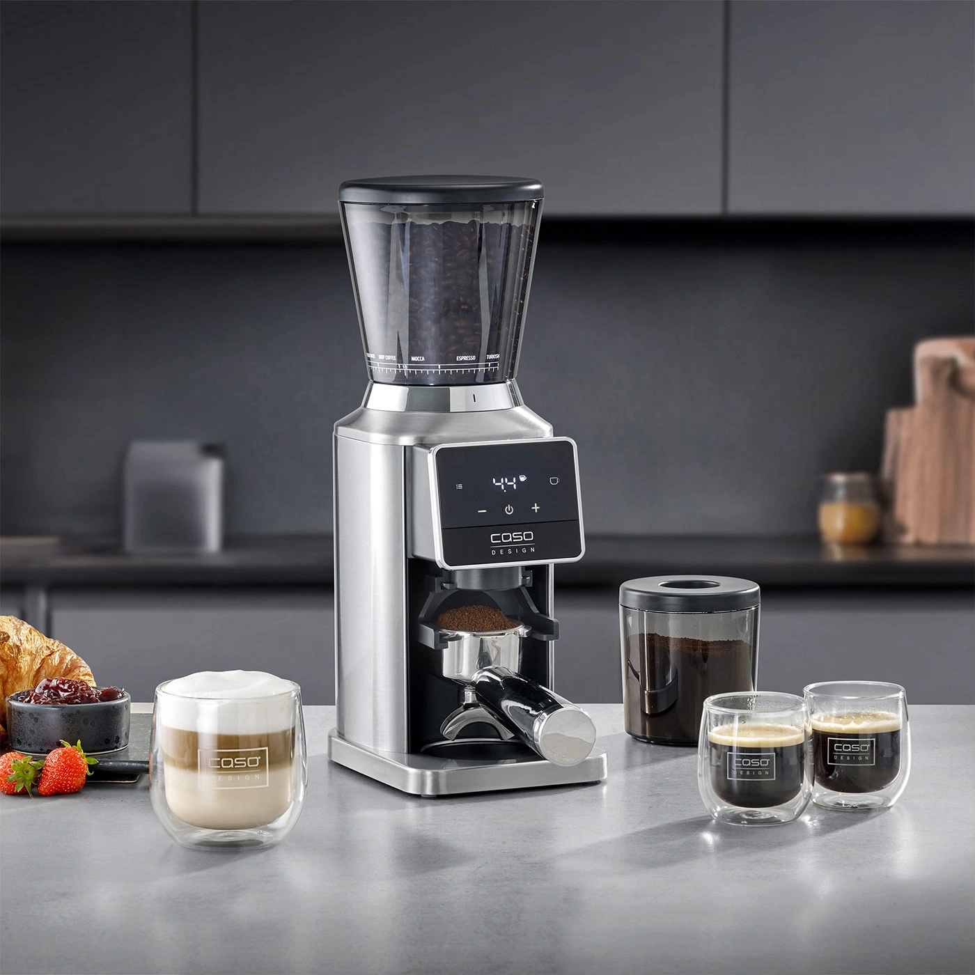 Kaffeemühle mit Kaffeebohnen, gemahlenem Kaffee und zwei Tassen Kaffee.