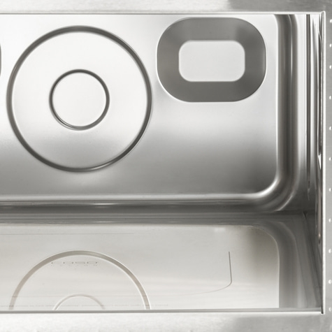 Stainless steel kitchen sink with circular and rectangular cutouts, close-up shot