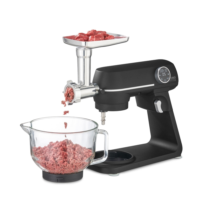 Fleischwolf mit Fleisch und Schüssel. Schwarze Küchenmaschine. Fleisch wird zerkleinert.
