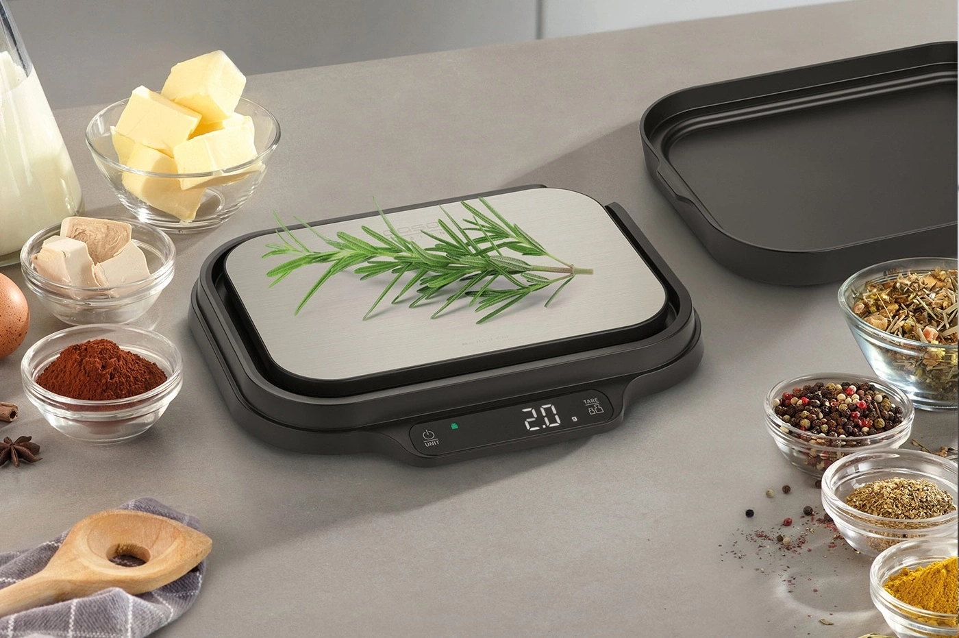 Kitchen scale with herbs and ingredients for cooking and baking on a table.